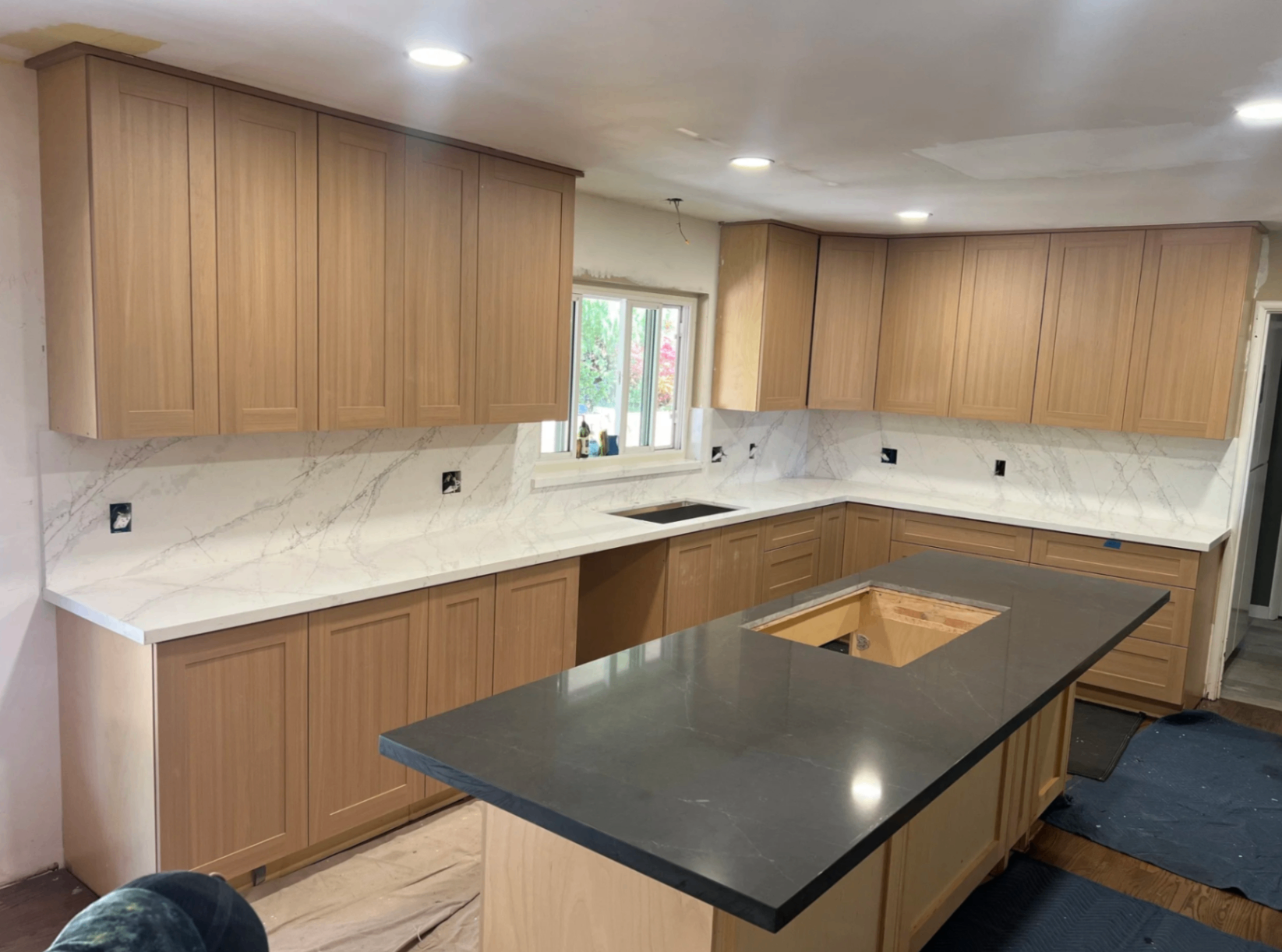 Charcoal quartz island with full-height veined backsplash
